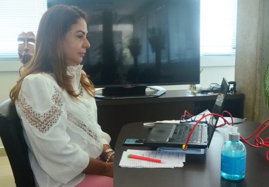 Fotografia da presidente, desembargadora Waldirene Cordeiro, sentada olhando pra a tela do notebook